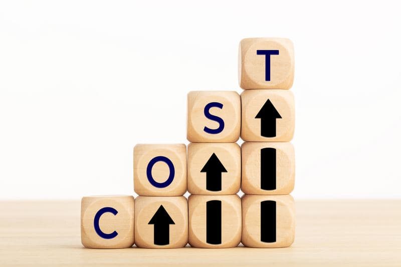 Wooden blocks spelling COST with upward arrows representing rising rental property expenses